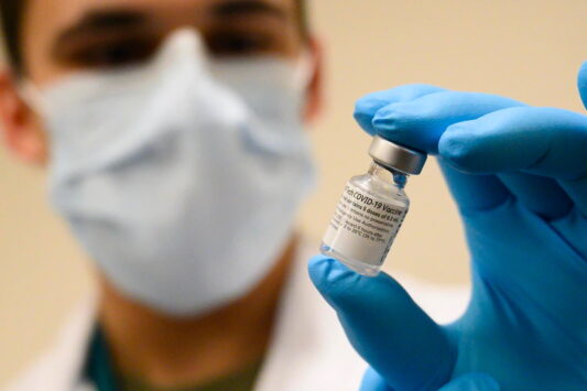 An army specialist holds a vial of a COVID-19 vaccine.